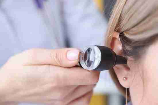 A person is having their ear examined with an otoscope by a healthcare professional.